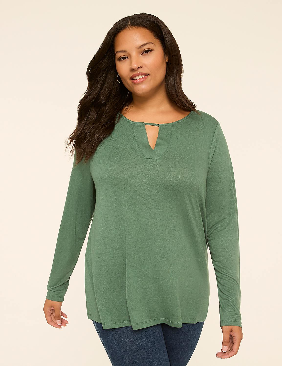 A woman with long, dark hair and a green, long-sleeved top stands against a plain, light-colored background. Product Image 1