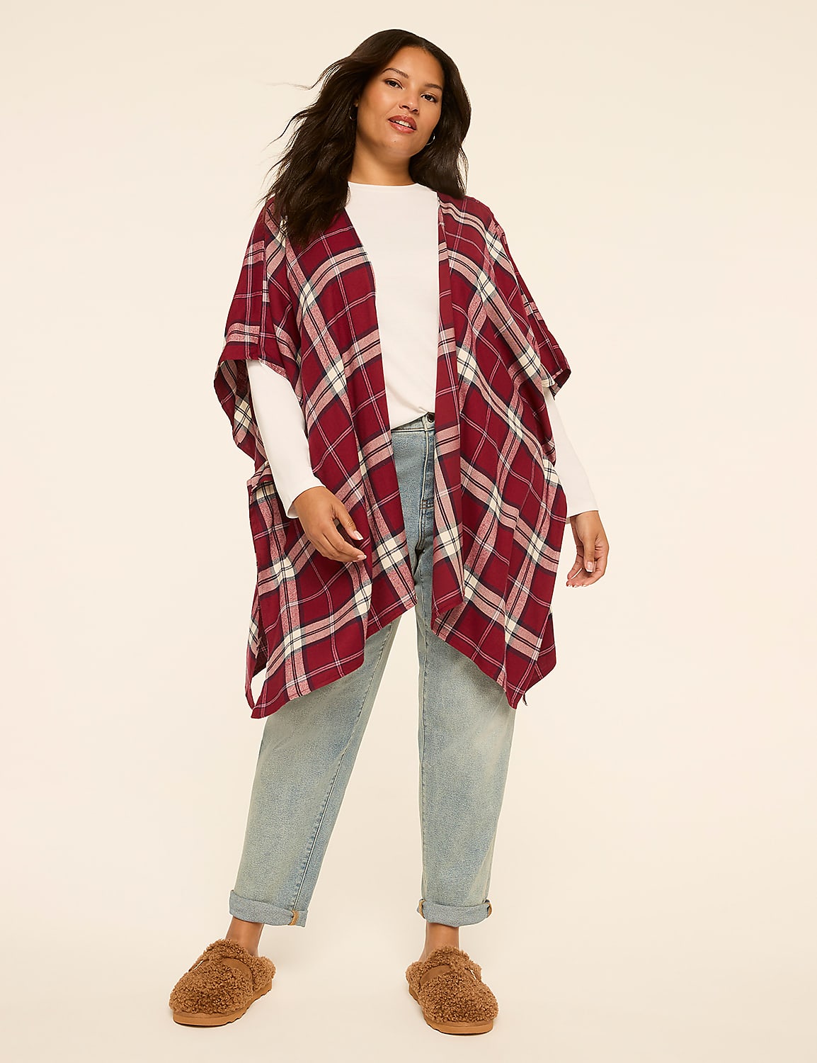 A woman in a plaid poncho and jeans stands against a plain, light-colored background. Product Image 1