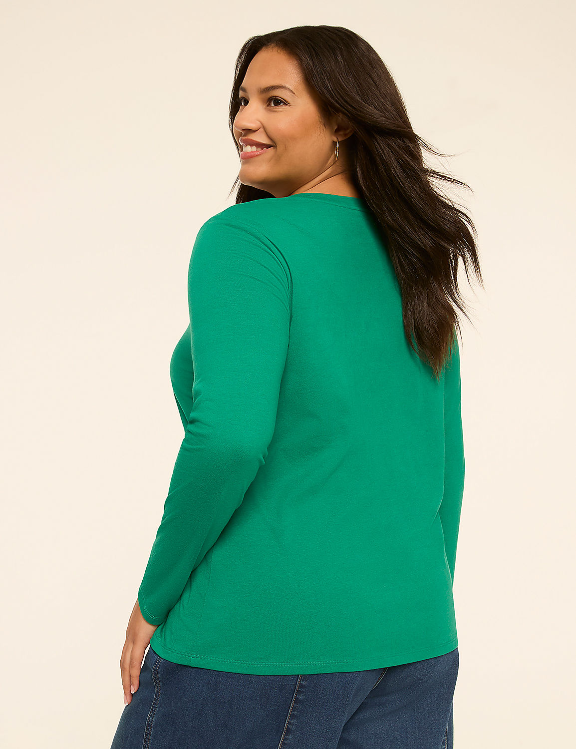 A woman in a green long-sleeved shirt and blue jeans stands against a plain, light-colored background. Product Image 2
