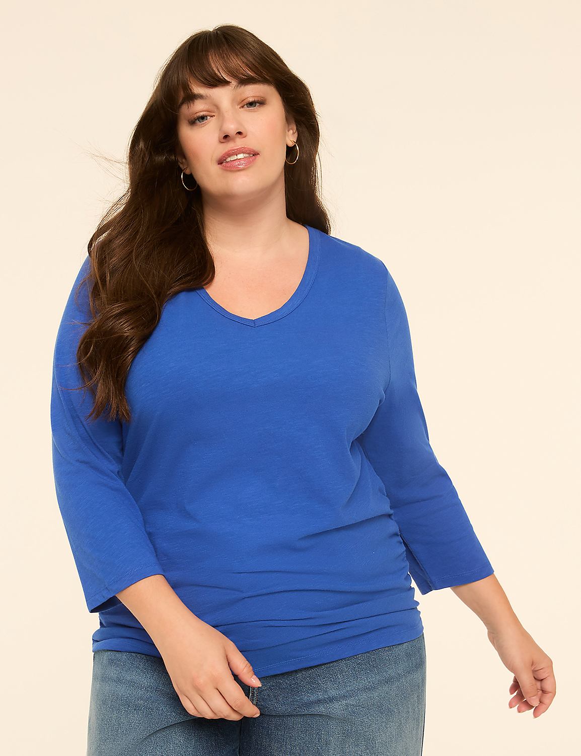 A woman in a blue shirt and jeans stands against a plain, light-colored background. Product Image 1