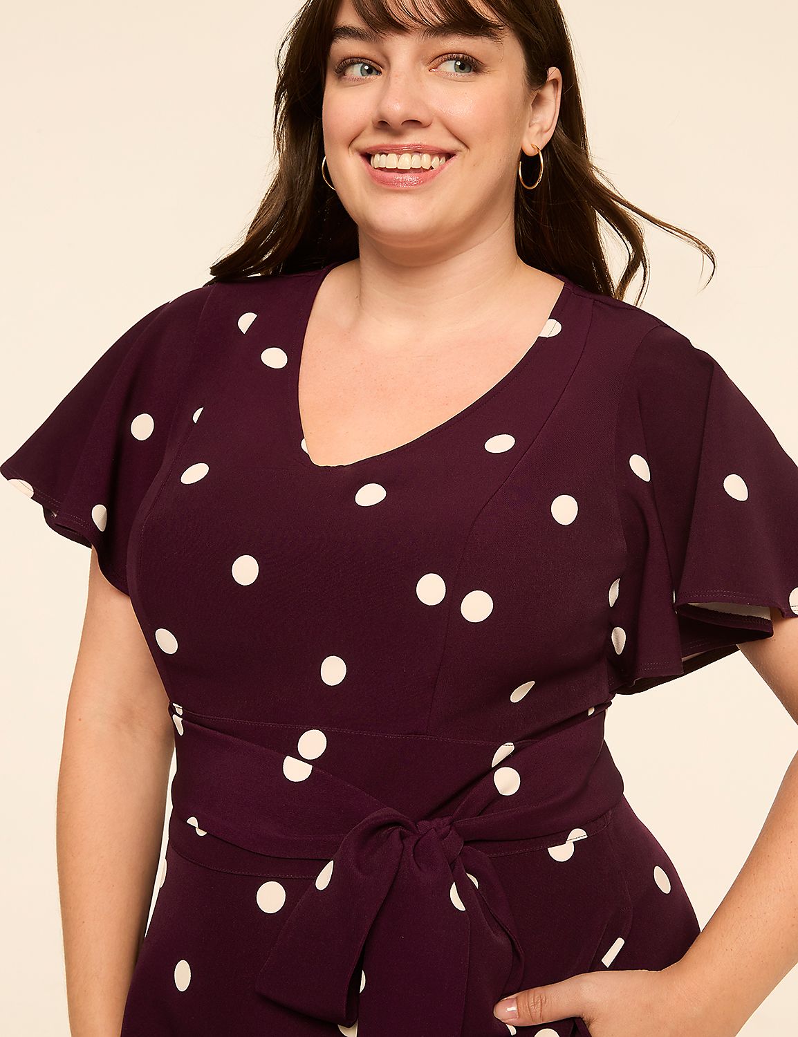 A smiling woman in a polka-dot dress stands against a plain, light-colored background. Product Image 3