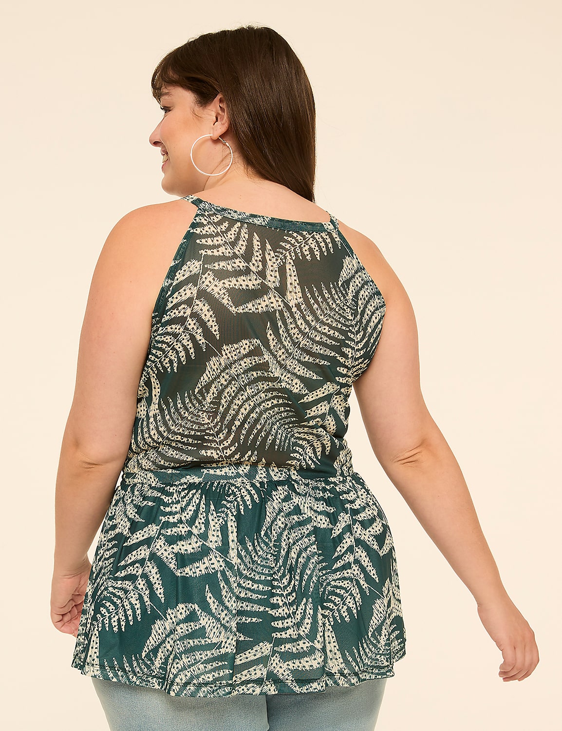 A woman in a green fern-patterned top stands against a plain, light-colored background. Product Image 2