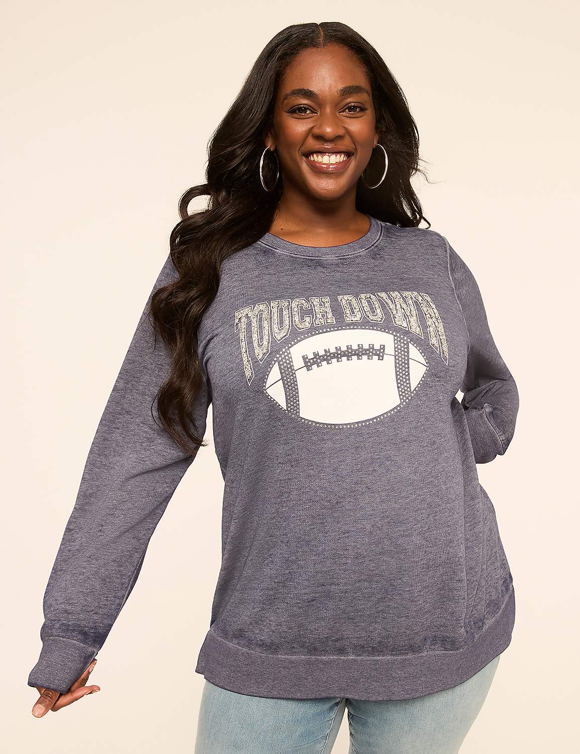 A smiling woman in a blue sweatshirt with a football graphic stands against a plain, light-colored background. Product Image 1