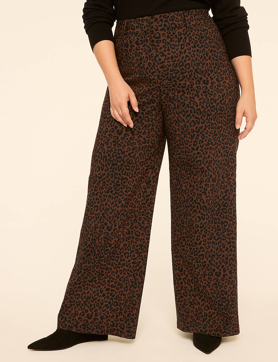 A person stands in the foreground wearing wide-leg leopard print pants and black boots, against a plain, light-colored background. Product Image 1