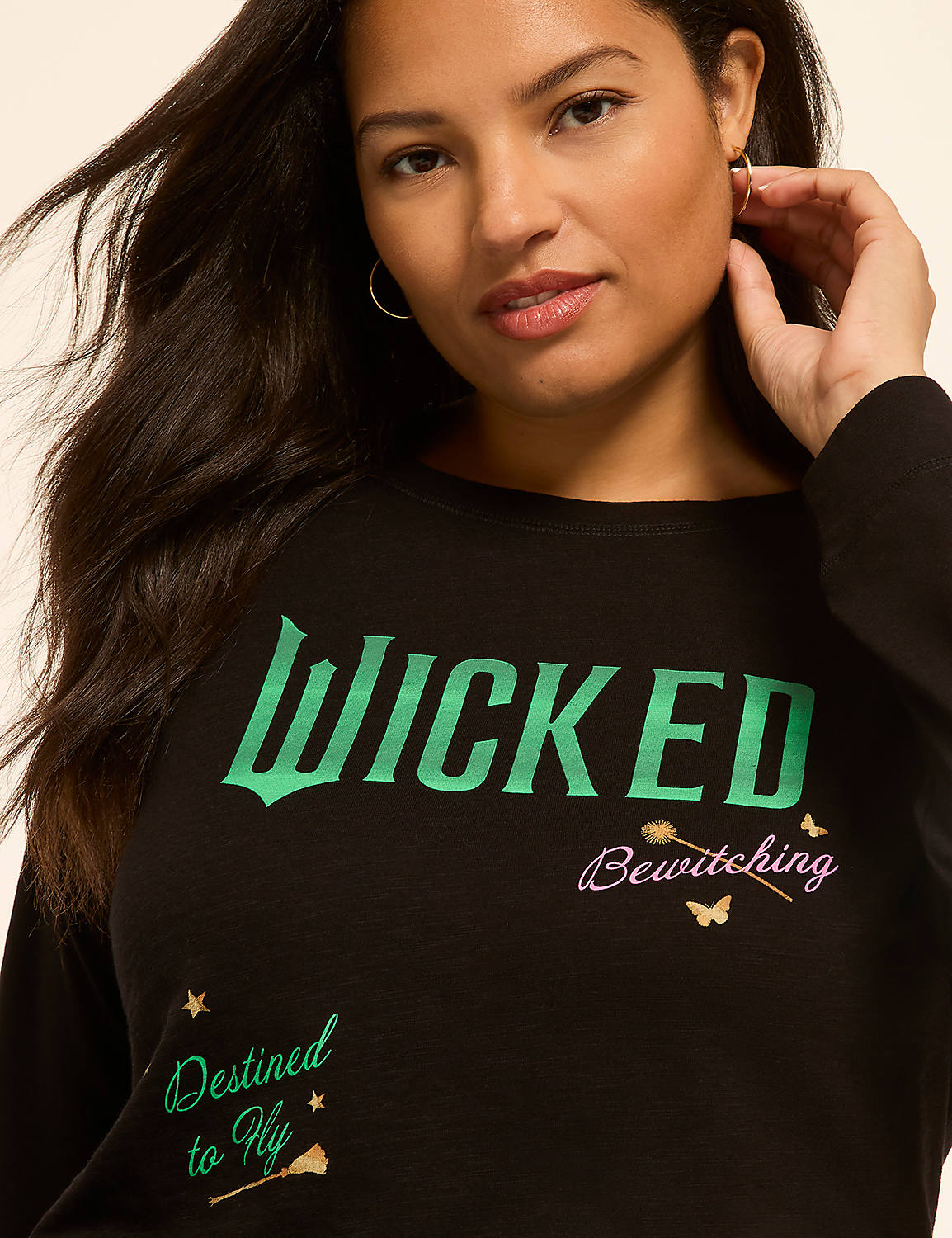 A woman with dark hair and hoop earrings smiles as she poses in front of a plain background, wearing a black shirt with "WICKED" and other phrases printed on it. Product Image 4