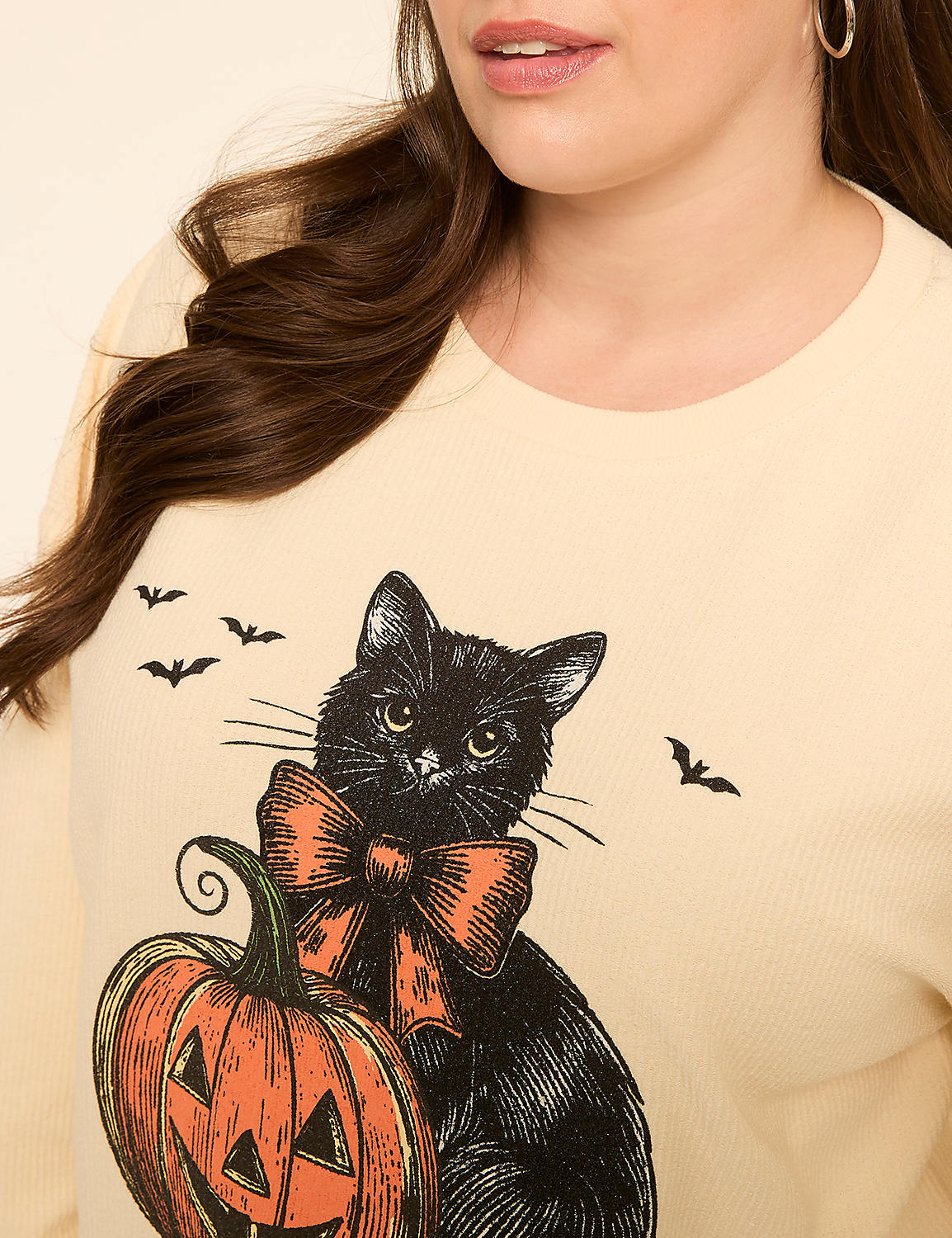 A black cat with an orange bow sits beside a jack-o'-lantern on a cream-colored shirt, with small bats flying in the background. Product Image 4
