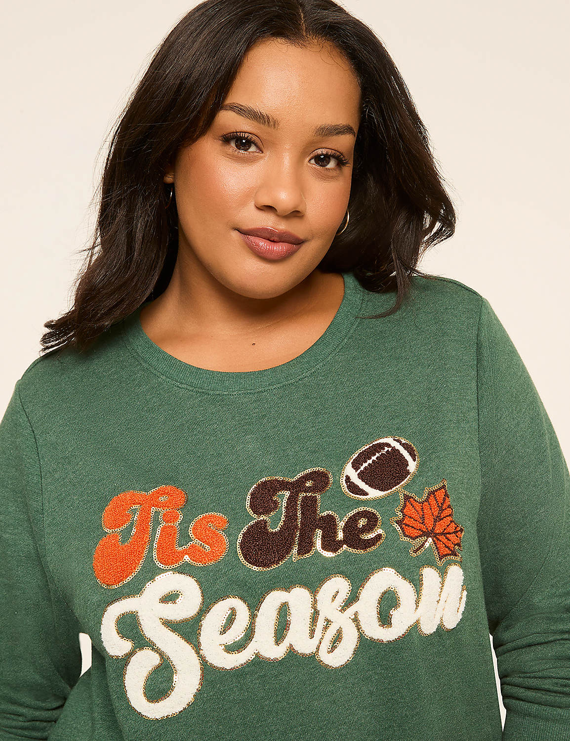 A woman in a green sweatshirt with a "Tis The Season" graphic featuring a football and autumn leaves smiles against a plain background. Product Image 4