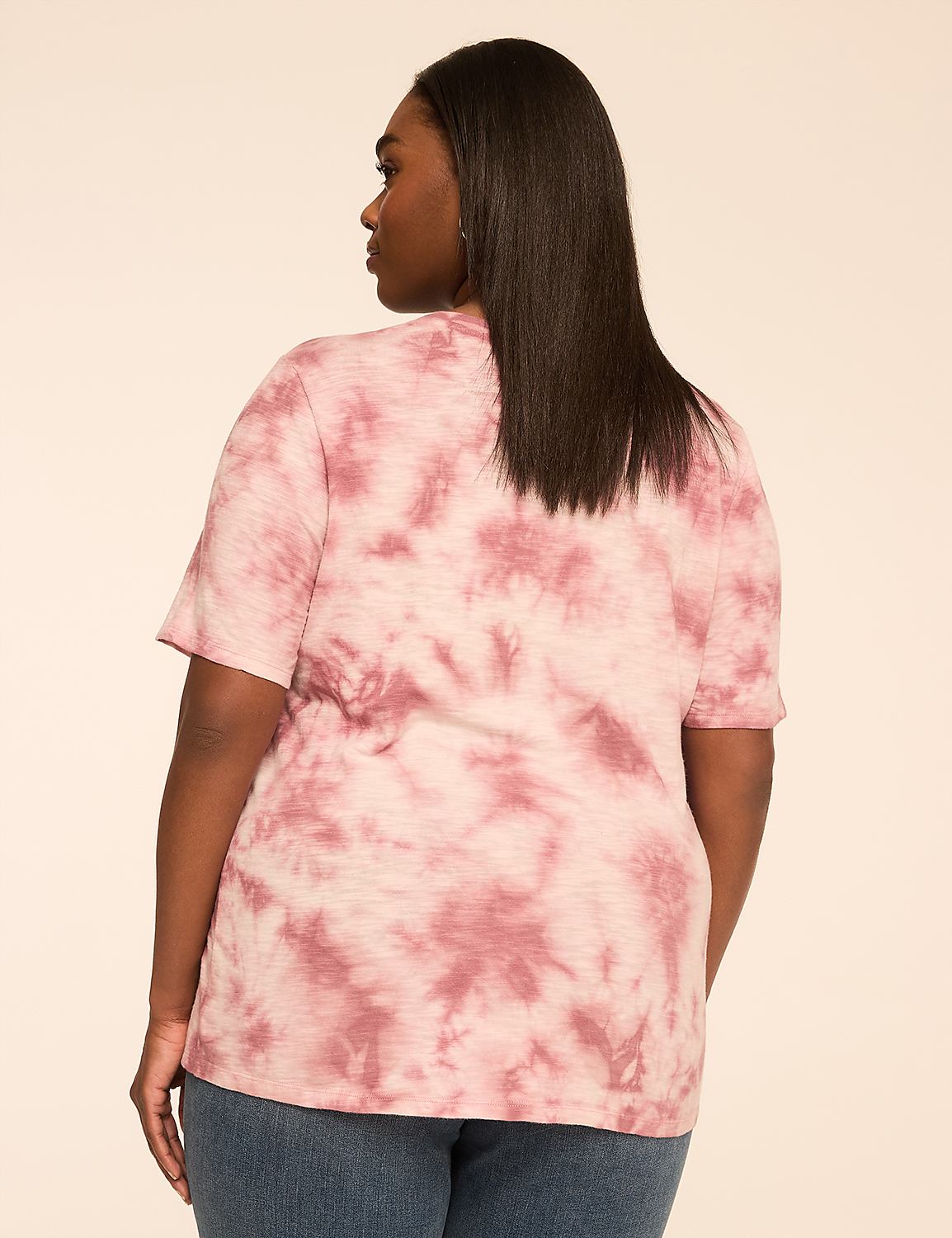 A woman in a pink tie-dye t-shirt and blue jeans stands against a plain, light brown background. Product Image 2