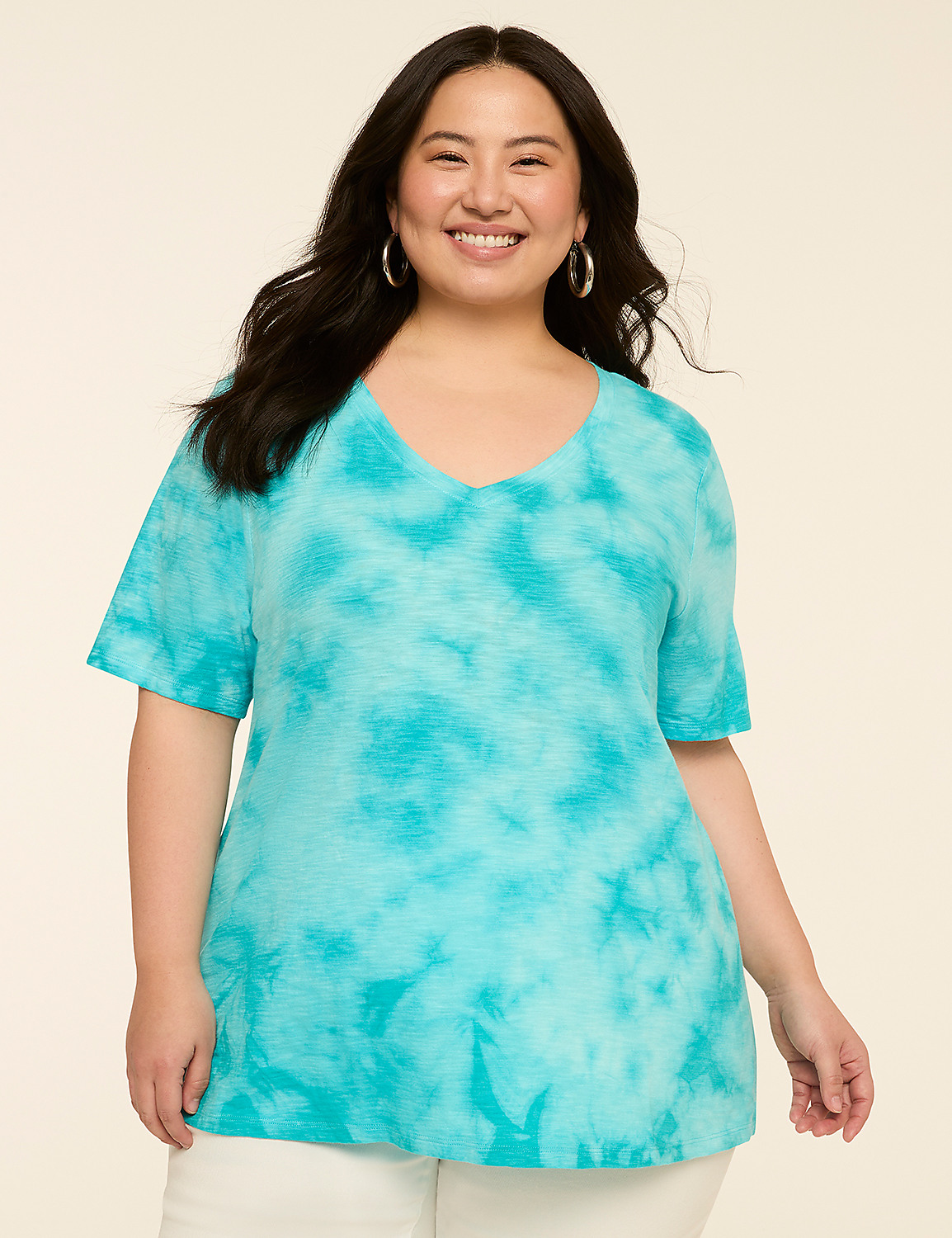 A smiling woman in a turquoise tie-dye v-neck shirt stands against a plain, light-colored background. Product Image 1