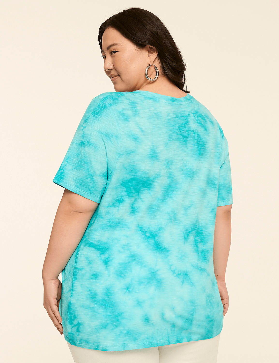 A woman in a turquoise tie-dye t-shirt stands against a plain, light-colored background. Product Image 2
