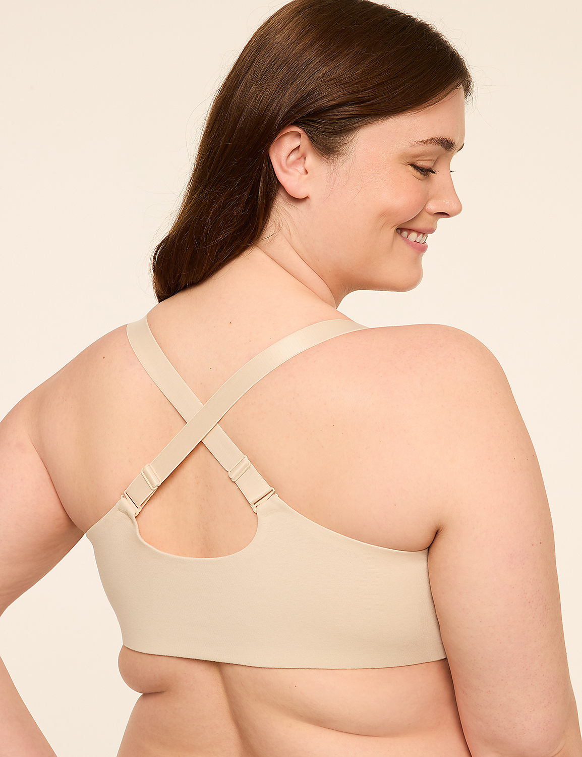 A woman with brown hair smiles as she wears a beige bra with criss-cross straps against a plain, light background. Product Image 2