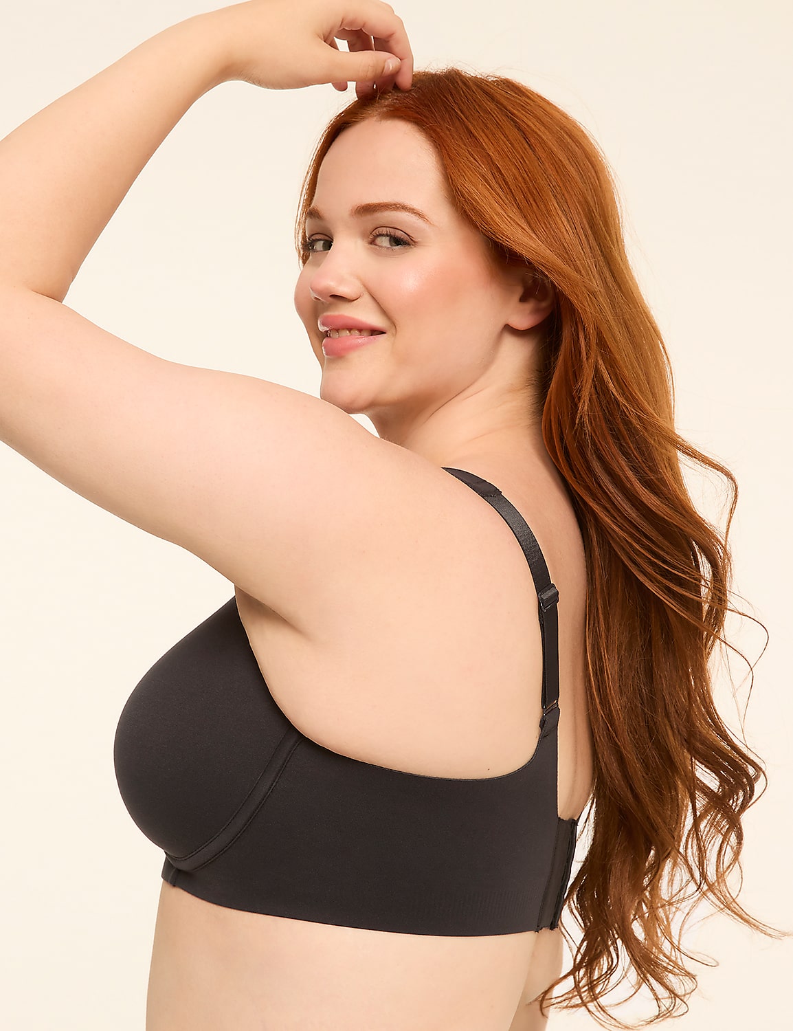 A woman with long red hair smiles over her shoulder, wearing a dark bra against a plain, light background. Product Image 3