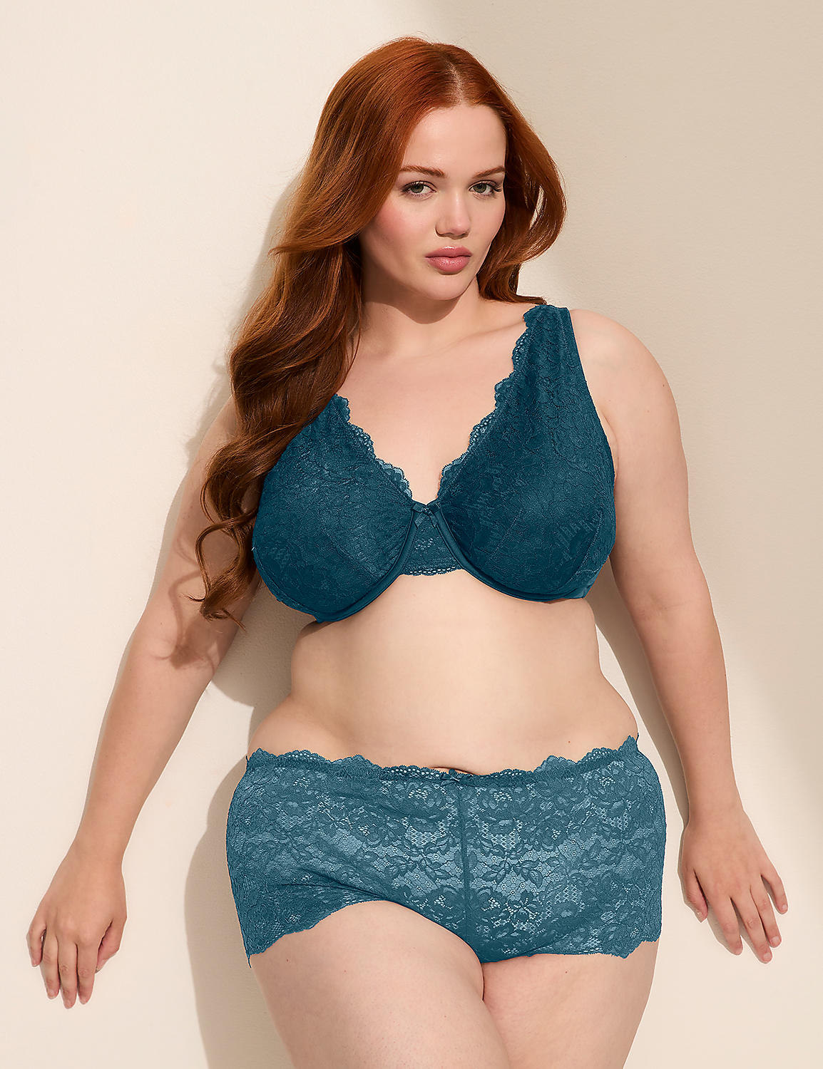 A red-haired woman in teal lace lingerie stands against a plain, light-colored wall. Product Image 4