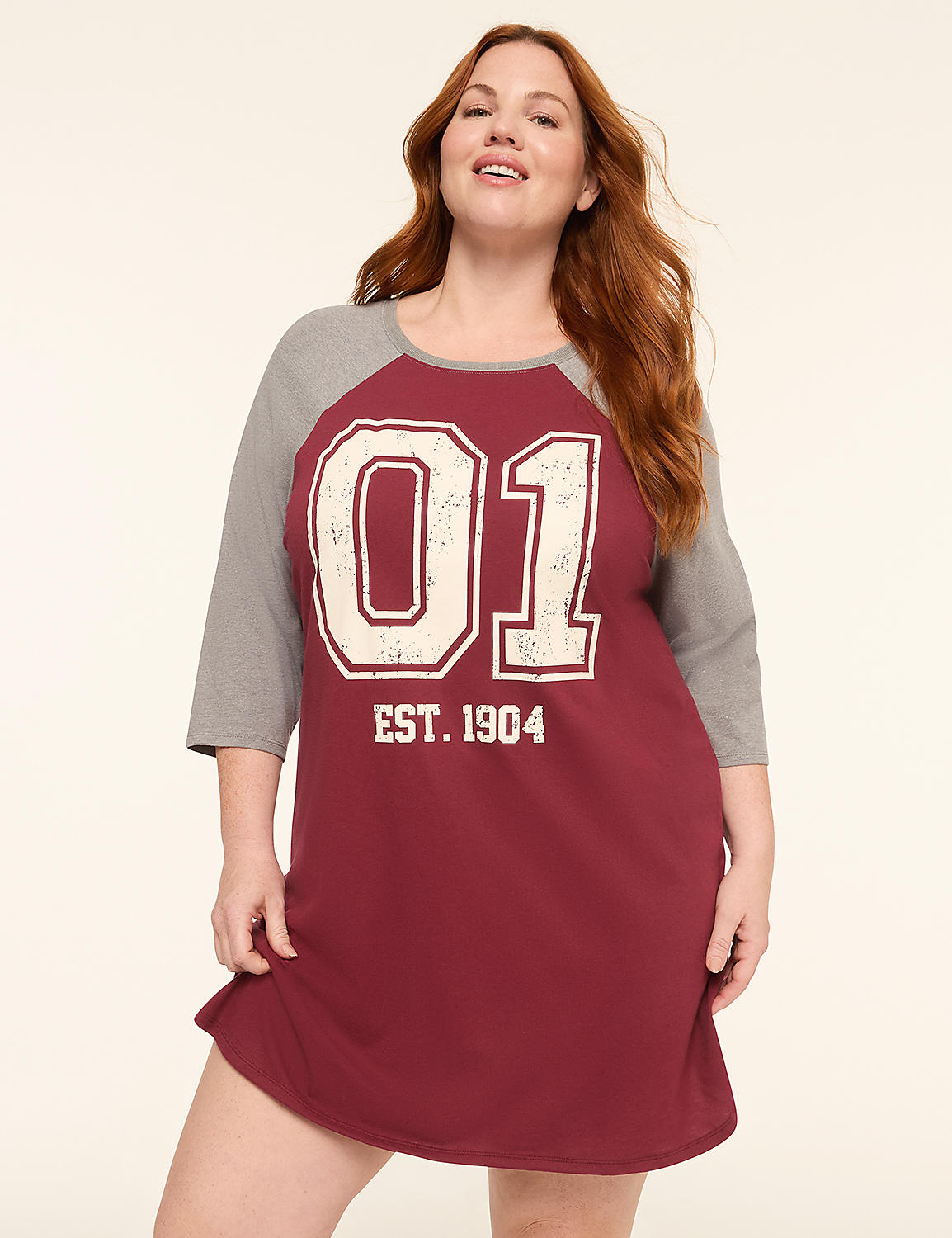 A woman with red hair smiles in a maroon and gray baseball-style nightgown with "01 EST. 1904" printed on it, against a plain, light-colored background. Product Image 1