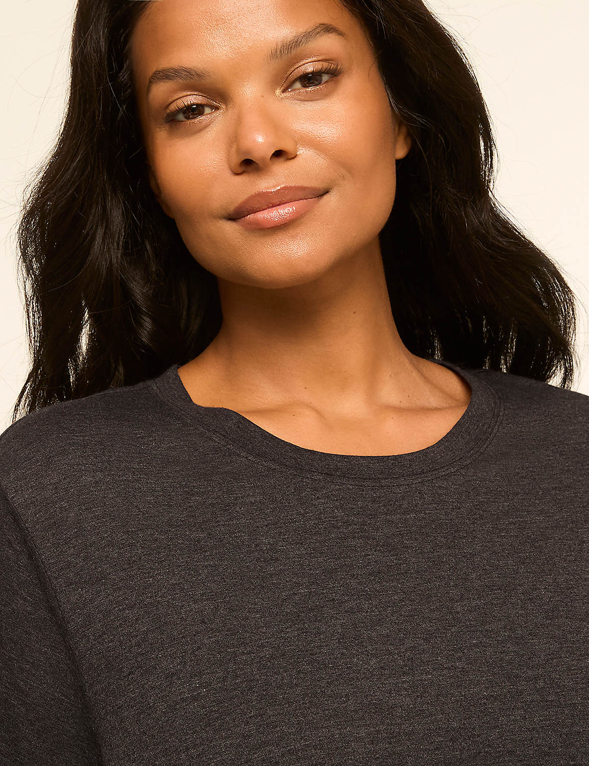 A woman with dark hair smiles gently in the foreground, her dark grey shirt visible against a soft, neutral background. Product Image 4
