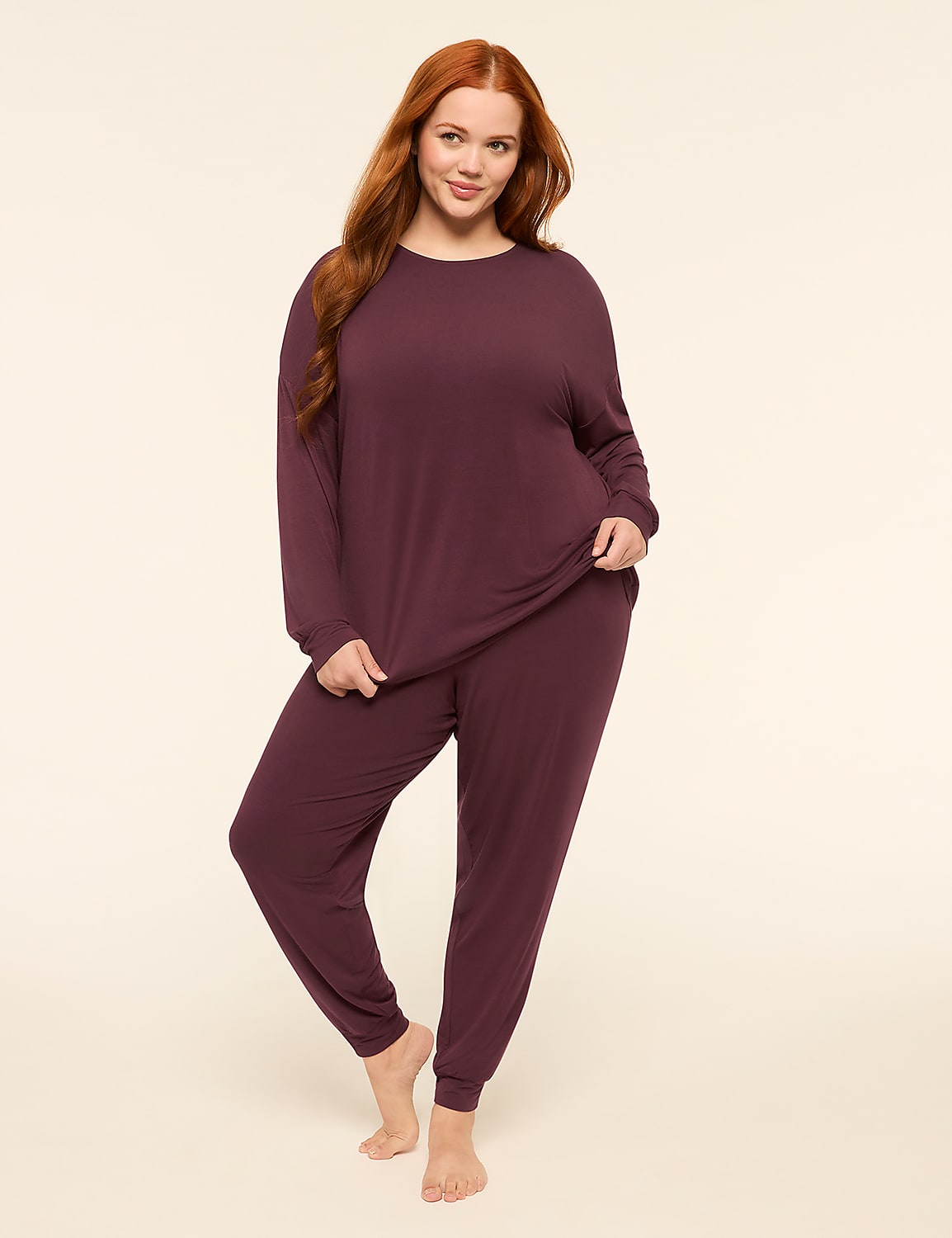 A woman with long red hair stands in a plum-colored pajama set against a plain, light-colored background. Product Image 1