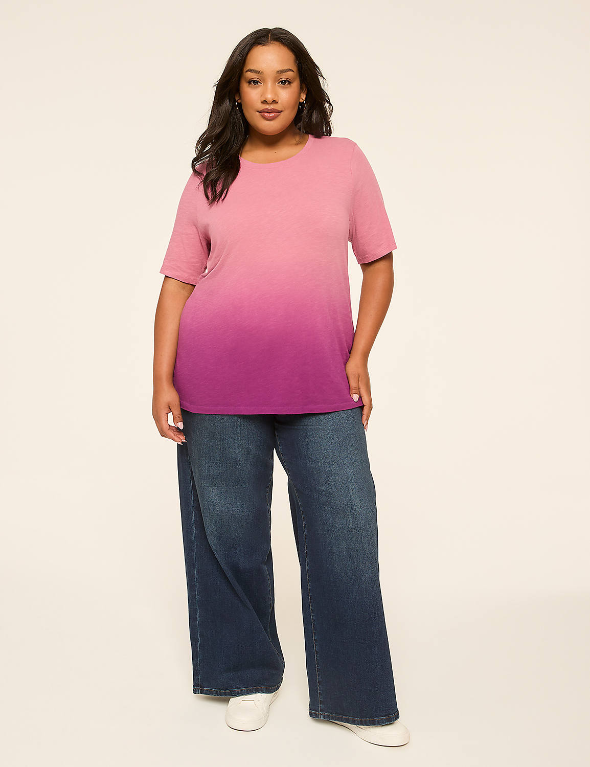 A woman in a pink and purple ombre t-shirt and wide-leg jeans stands against a plain, light-colored background. Product Image 3
