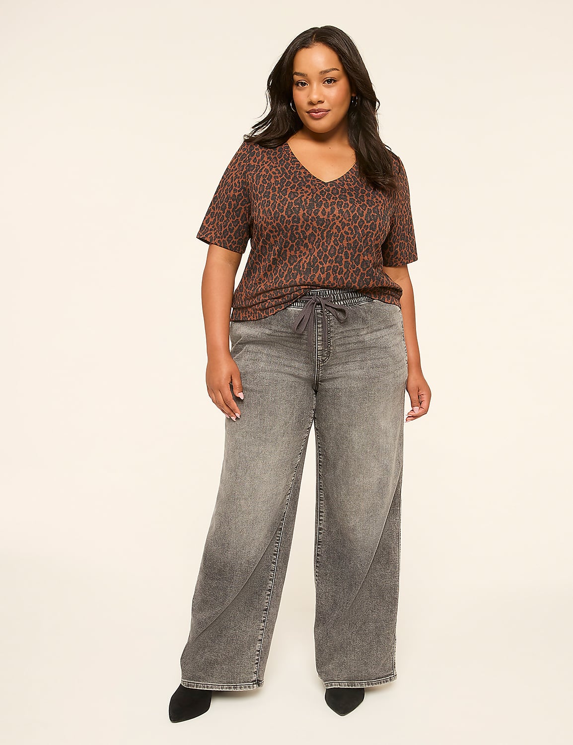 A woman in a leopard print top and wide-leg jeans stands against a plain, light-colored background. Product Image 3