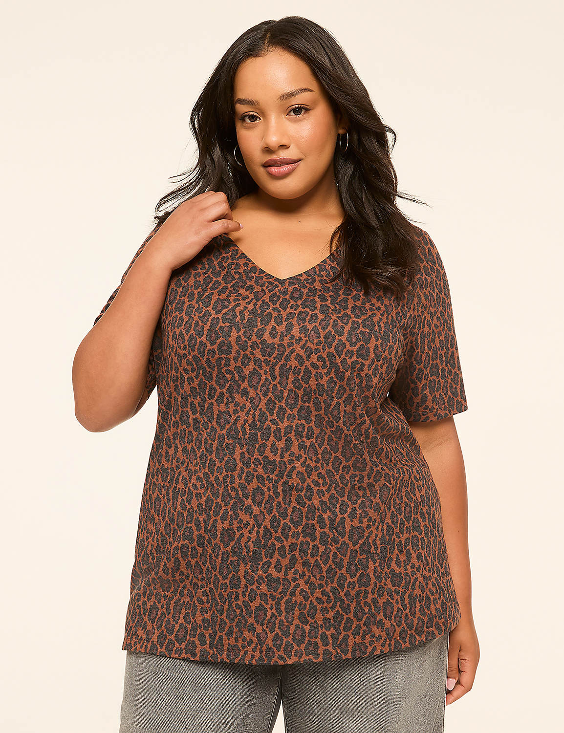 A woman in a leopard print v-neck shirt stands against a plain, light-colored background. Product Image 1