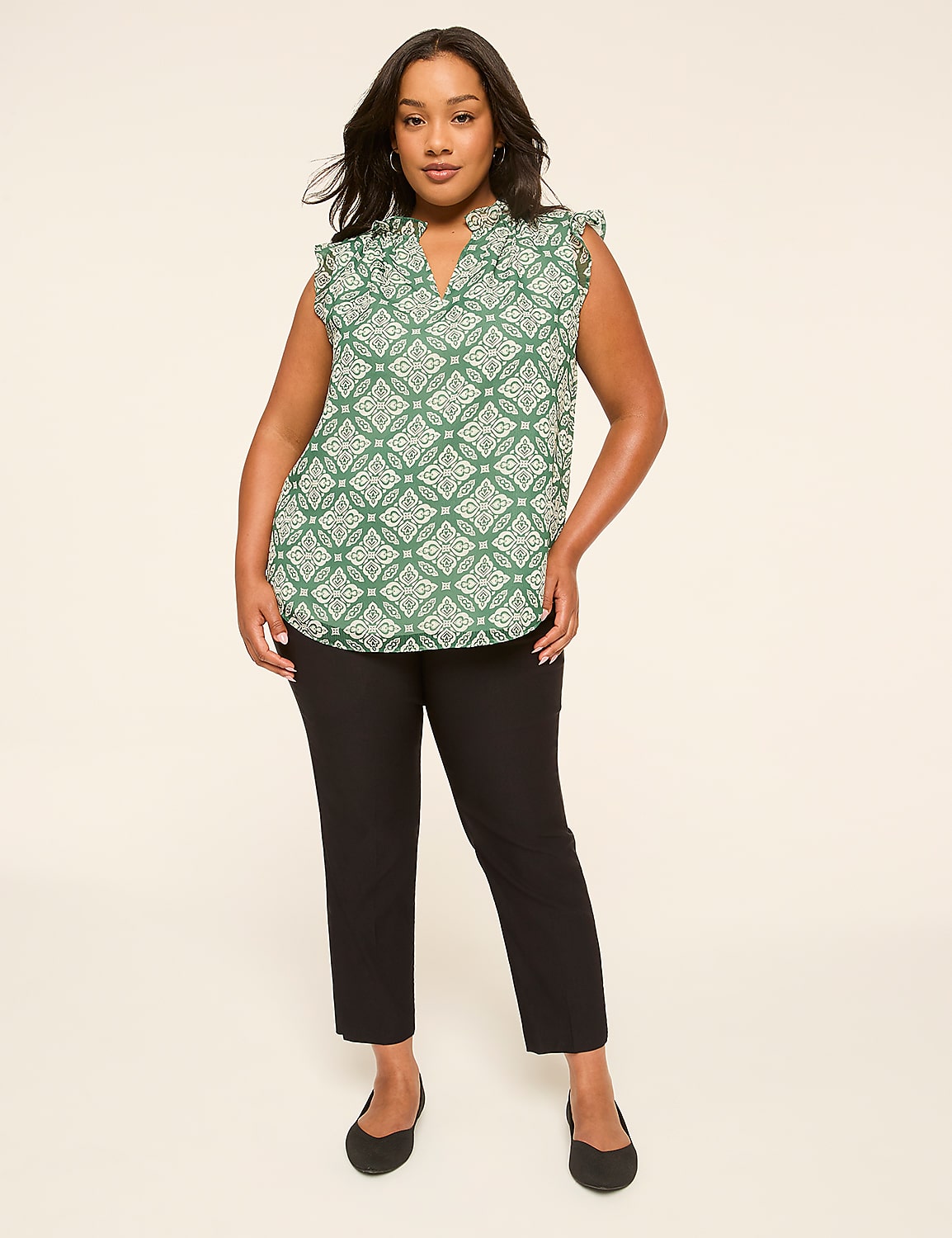 A woman in a green patterned top and black pants stands against a plain, light background. Product Image 3