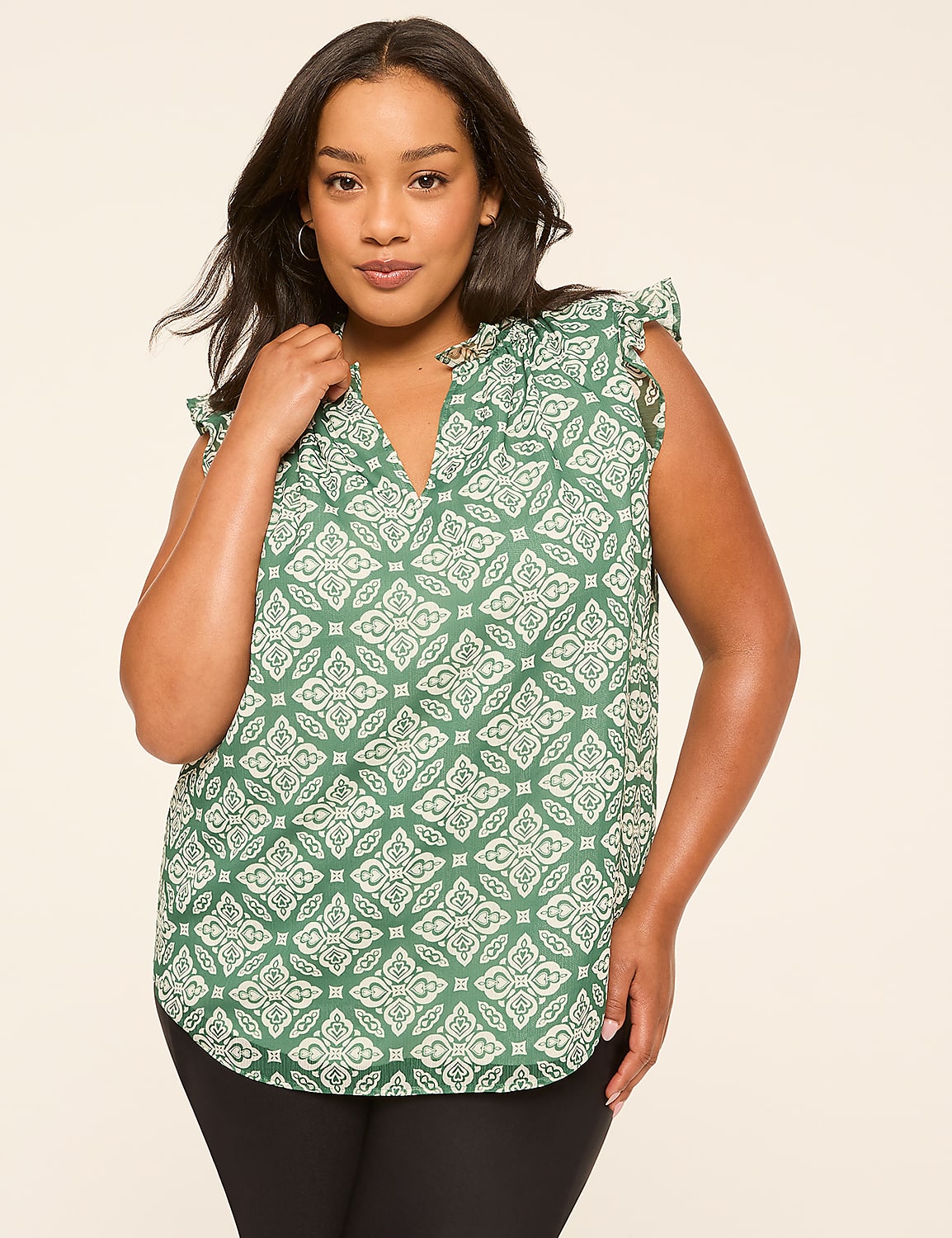 A woman in a green patterned blouse stands against a plain, light-colored background. Product Image 1