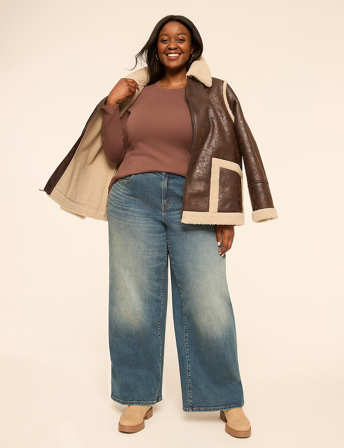 A smiling woman in a brown shearling jacket and wide-leg jeans stands against a plain, light-colored background. Product Image 3