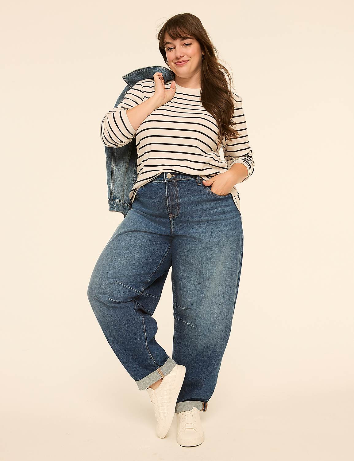 A woman in a striped shirt and baggy jeans stands against a plain, light-colored background, with a denim jacket slung over her shoulder. Product Image 3
