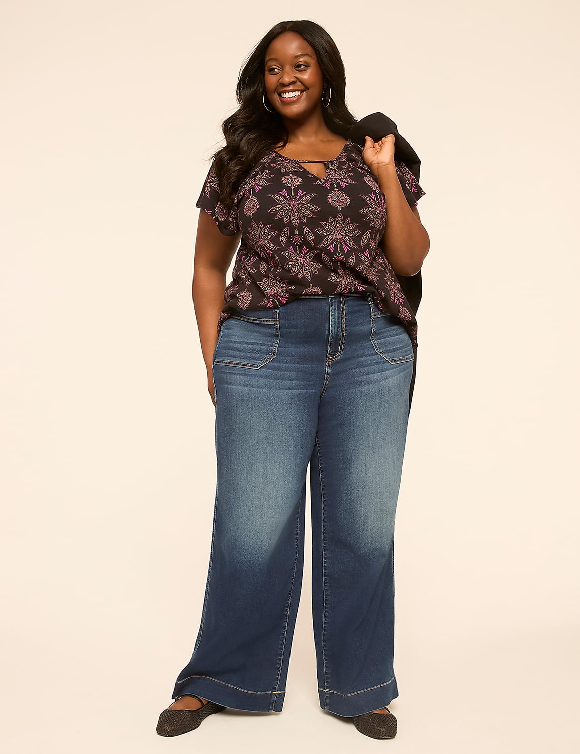 A smiling woman in a patterned top and wide-leg jeans stands against a plain, light-colored background. Product Image 3