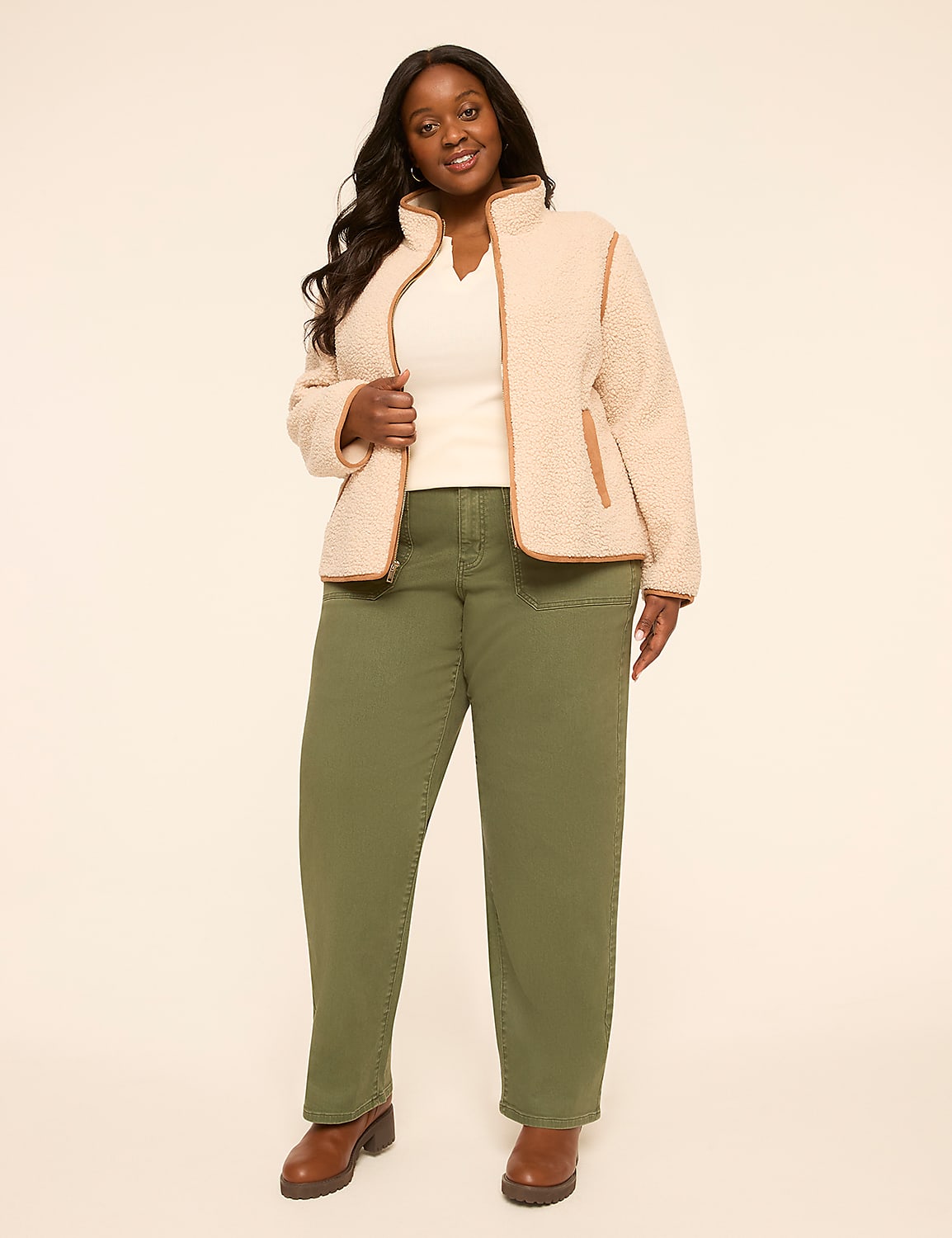 A smiling woman in a cream sherpa jacket and olive green pants stands against a plain, light-colored background. Product Image 3