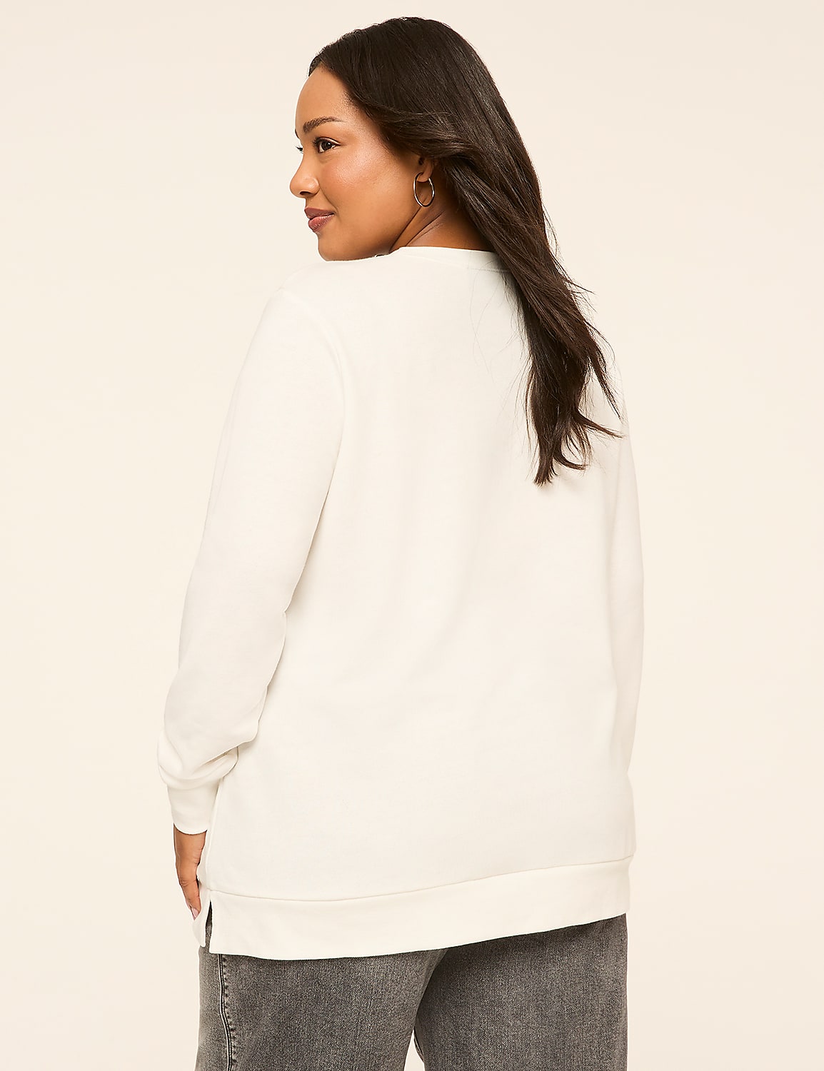 A woman in a white sweatshirt and grey jeans stands against a plain, light-colored background. Product Image 2