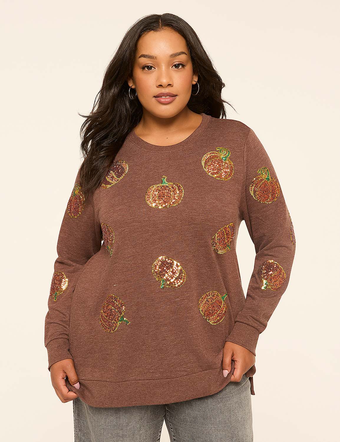 A woman in a brown sequined pumpkin sweatshirt stands against a plain, light-colored background. Product Image 1
