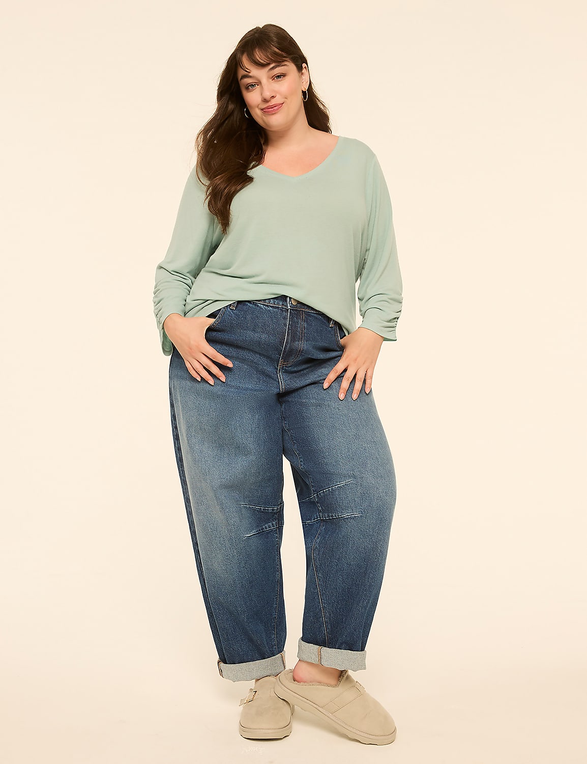 A woman in a light green v-neck shirt and baggy jeans stands with her hands in her pockets against a plain, light-colored background. Product Image 3