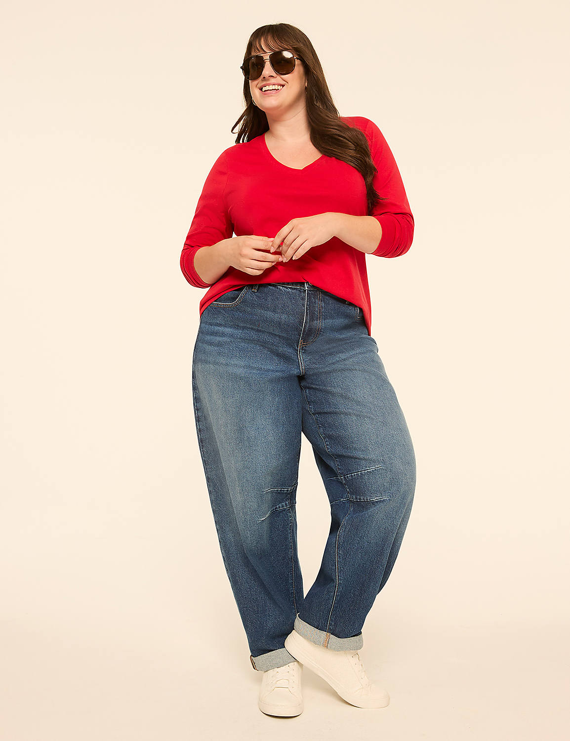 A smiling woman in a red sweater and baggy jeans stands against a plain, light-colored background. Product Image 3