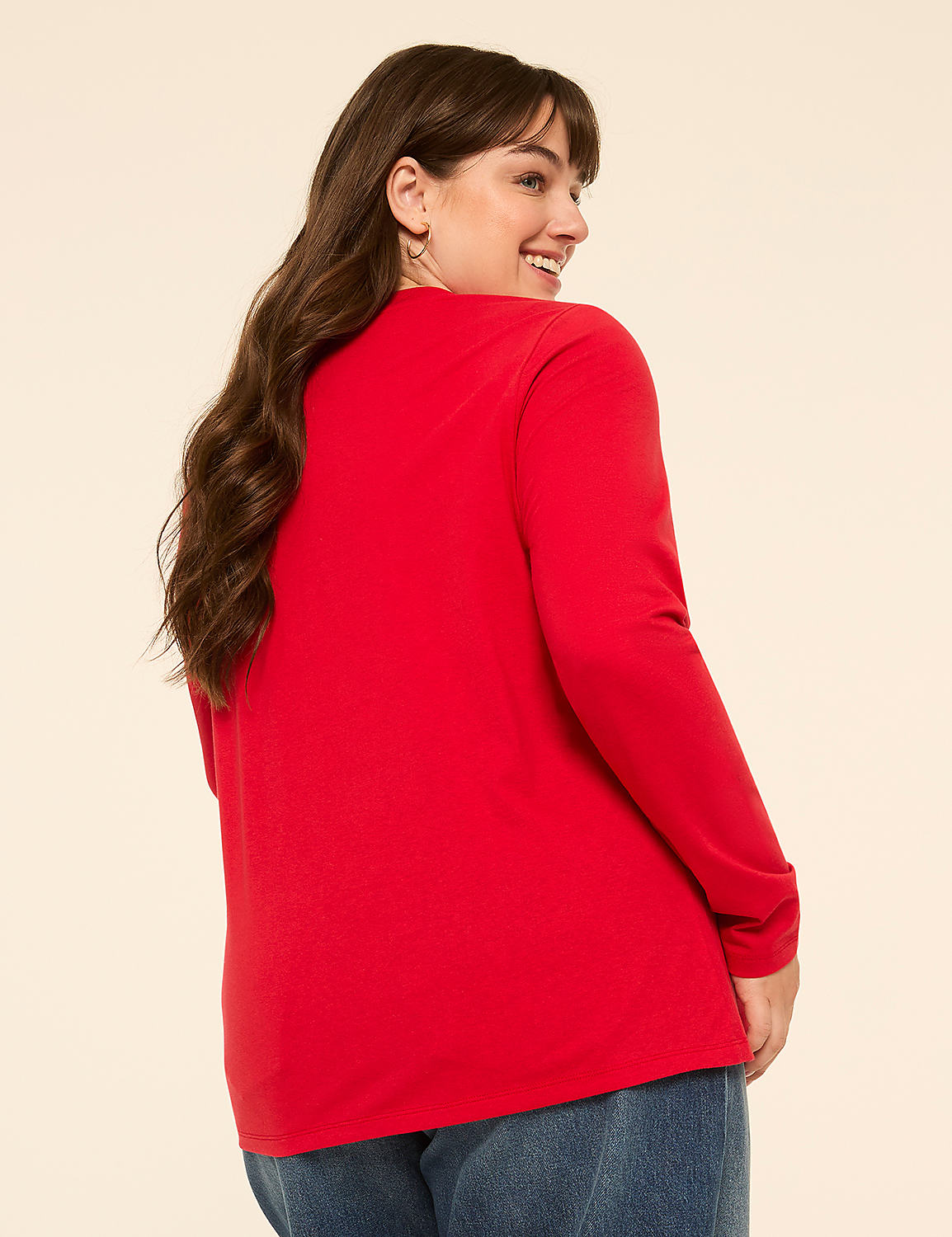 A woman in a red shirt and blue jeans smiles over her shoulder against a plain, light background. Product Image 2