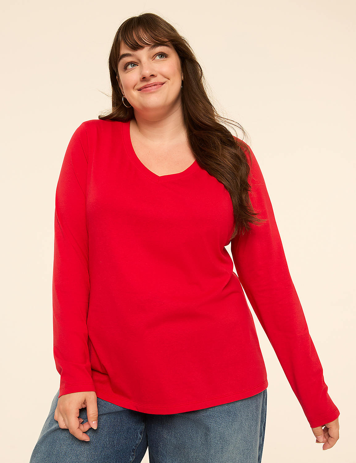 A smiling woman in a red long-sleeved shirt and blue jeans stands against a plain, light-colored background. Product Image 1