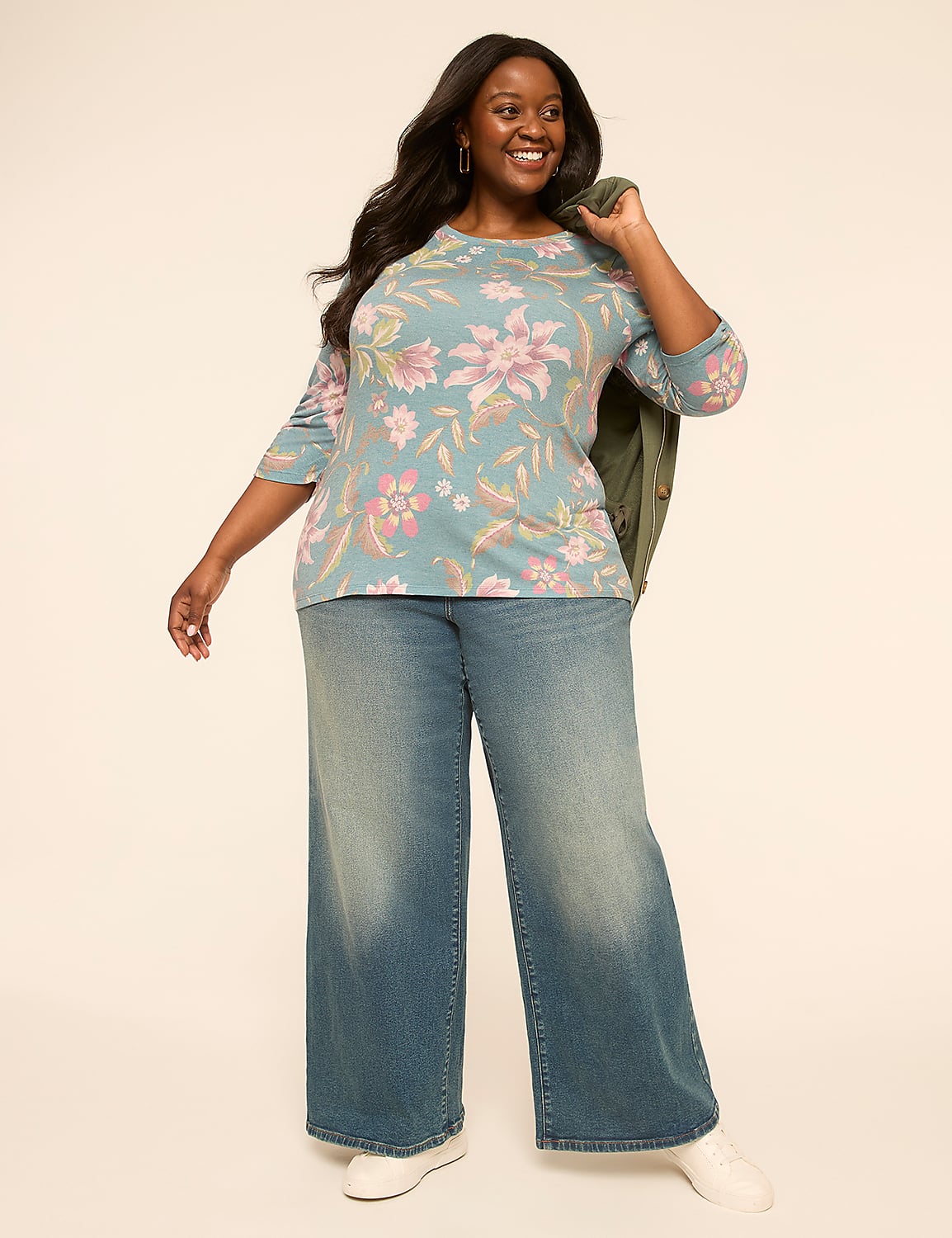 A smiling woman in a floral top and wide-leg jeans stands against a plain, light-colored background. Product Image 3
