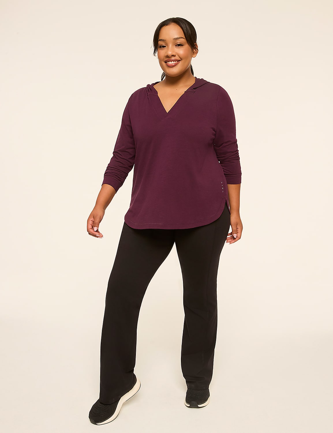 A smiling woman in a burgundy hooded shirt and black pants stands against a plain, light-colored background. Product Image 3