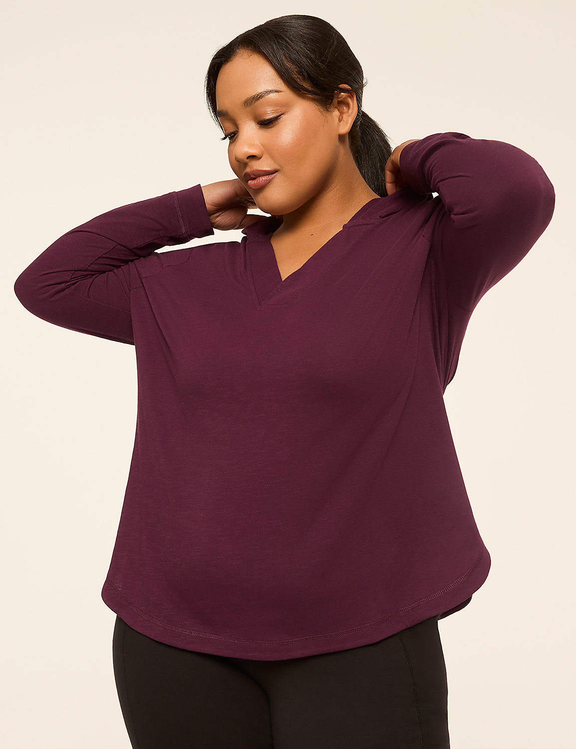 A woman in a purple hoodie adjusts her collar against a plain beige background. Product Image 1