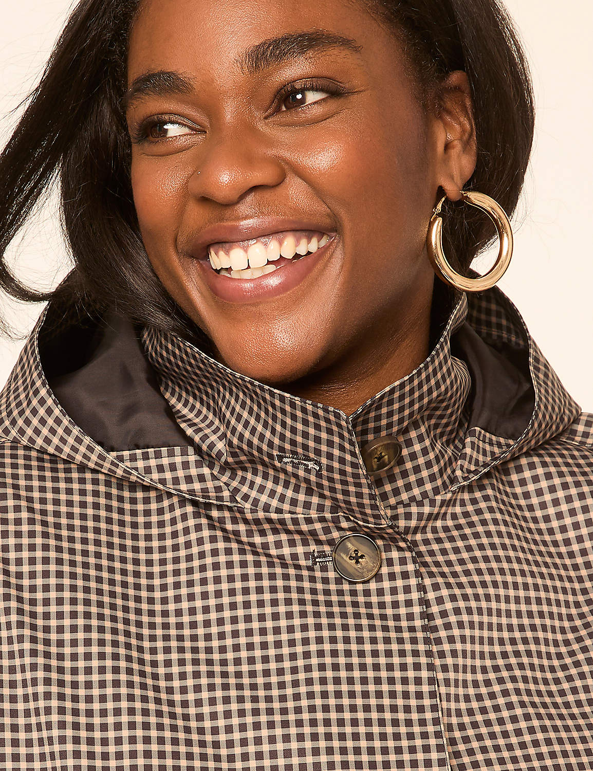 A smiling Black woman with large hoop earrings wears a brown and white checkered hooded jacket against a plain background. Product Image 4