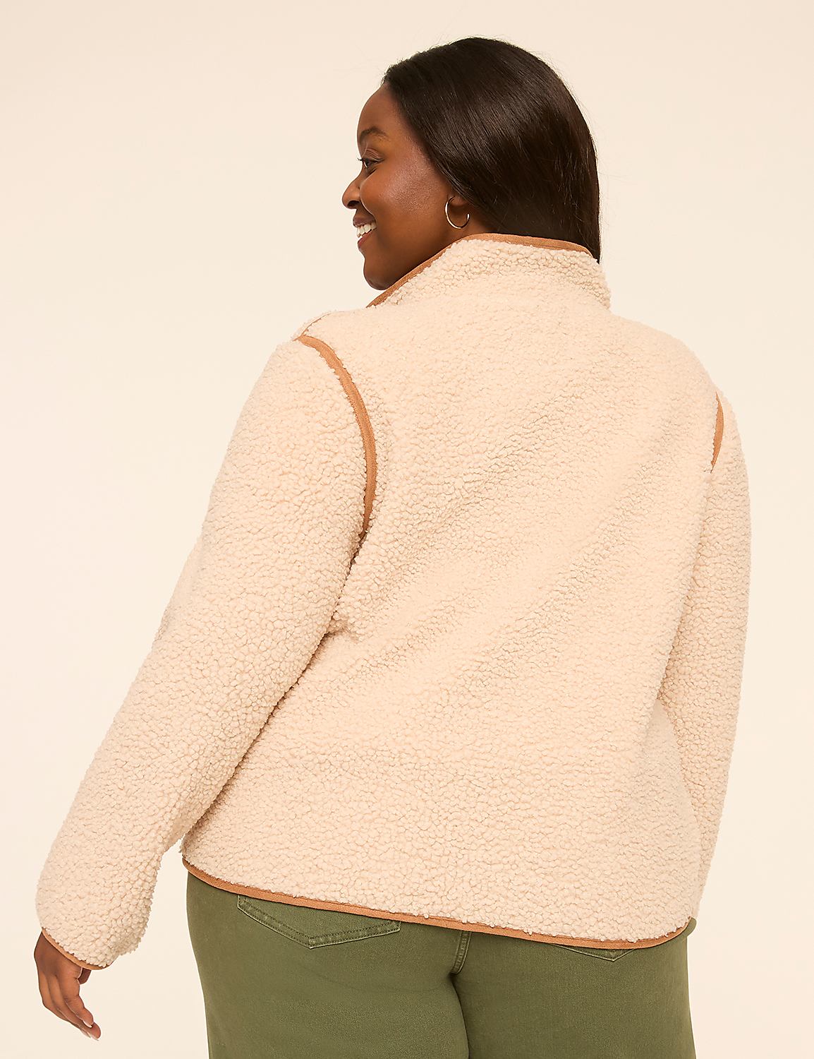 A woman in a cream-colored fuzzy jacket and green pants smiles over her shoulder against a plain beige background. Product Image 2