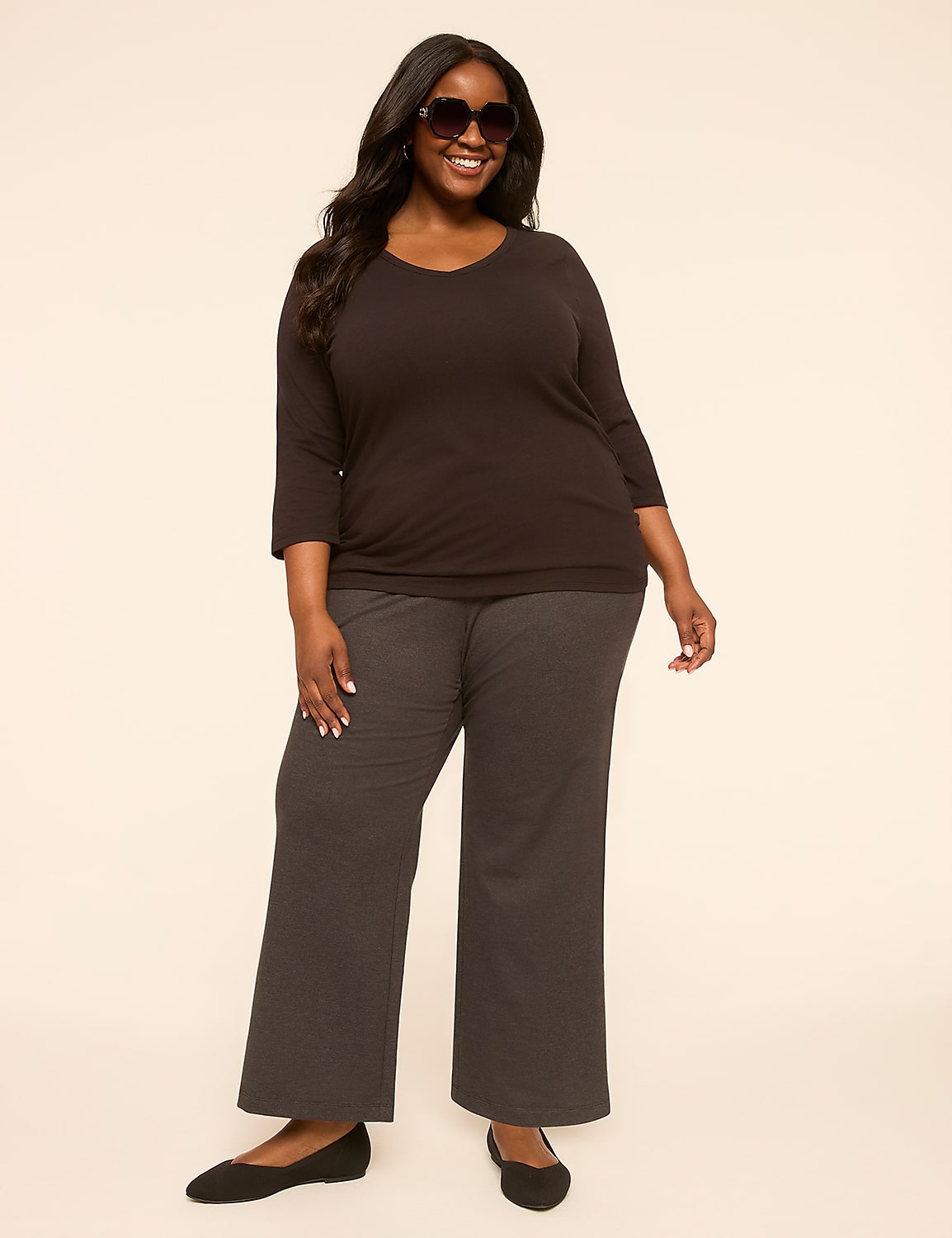 A smiling, plus-size woman in a dark top and patterned pants stands against a plain, light-colored background. Product Image 3