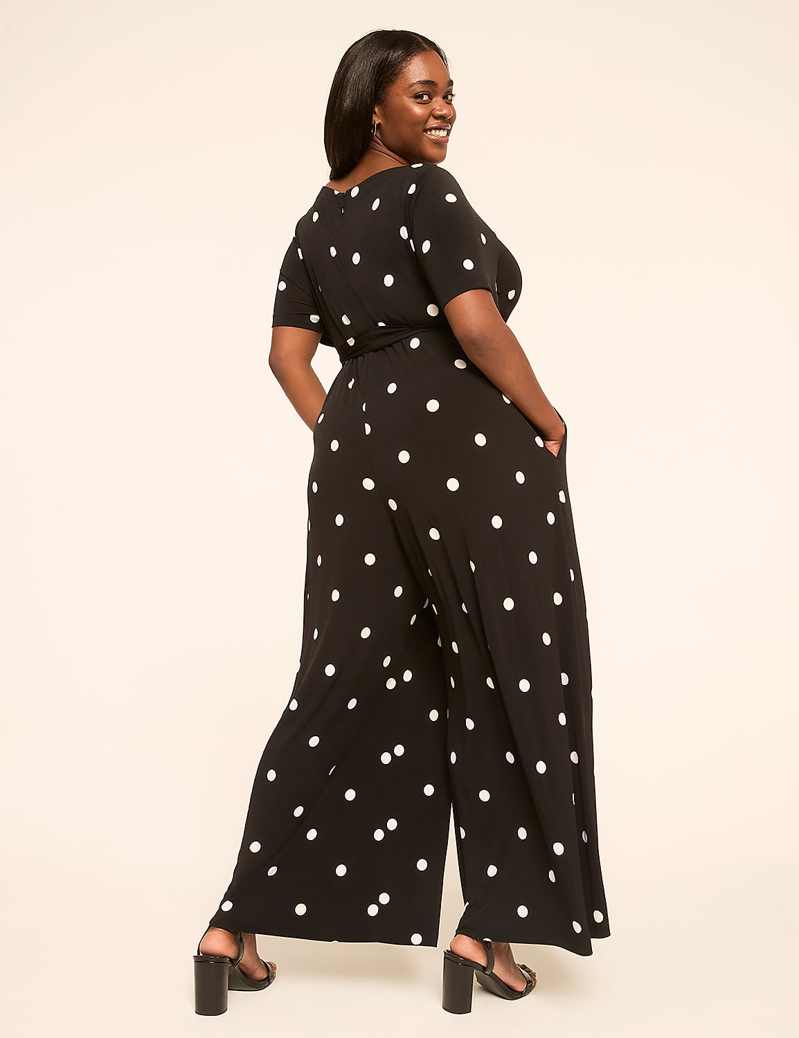 A woman in a black and white polka dot jumpsuit poses against a plain, light-colored background. Product Image 2