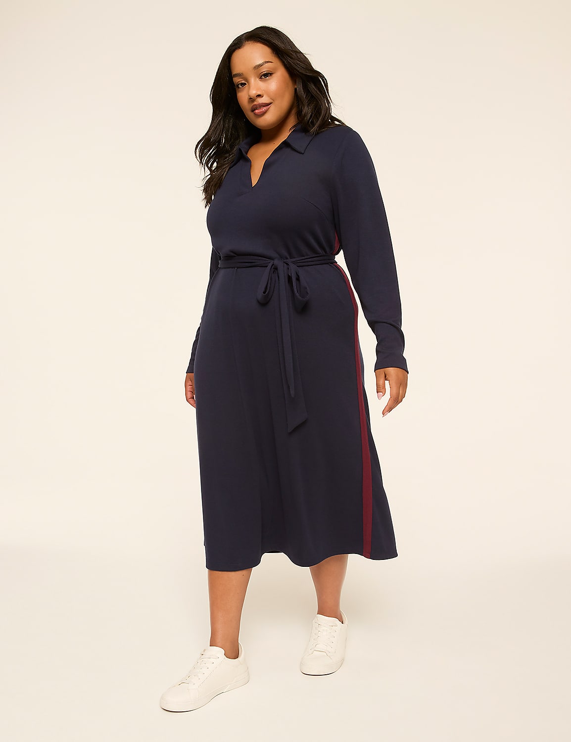 A woman in a navy dress and white sneakers stands against a plain, light-colored background. Product Image 1
