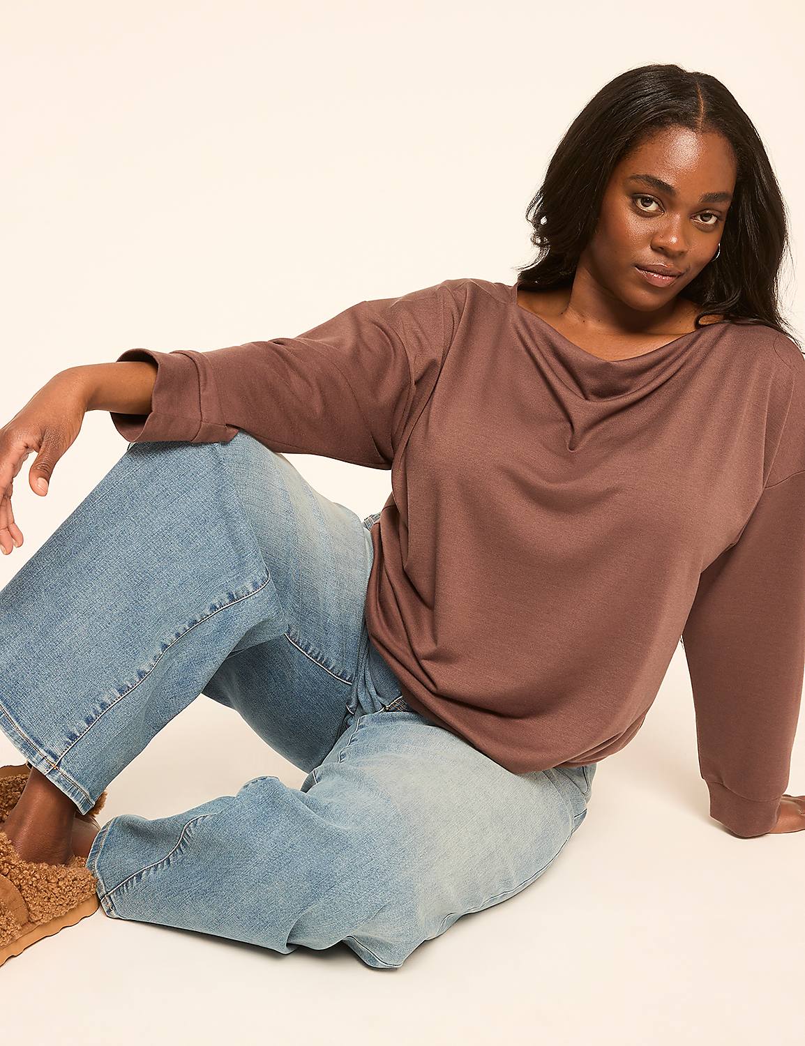A woman in a brown top and blue jeans sits on a light brown rug against a plain beige background. Product Image 3