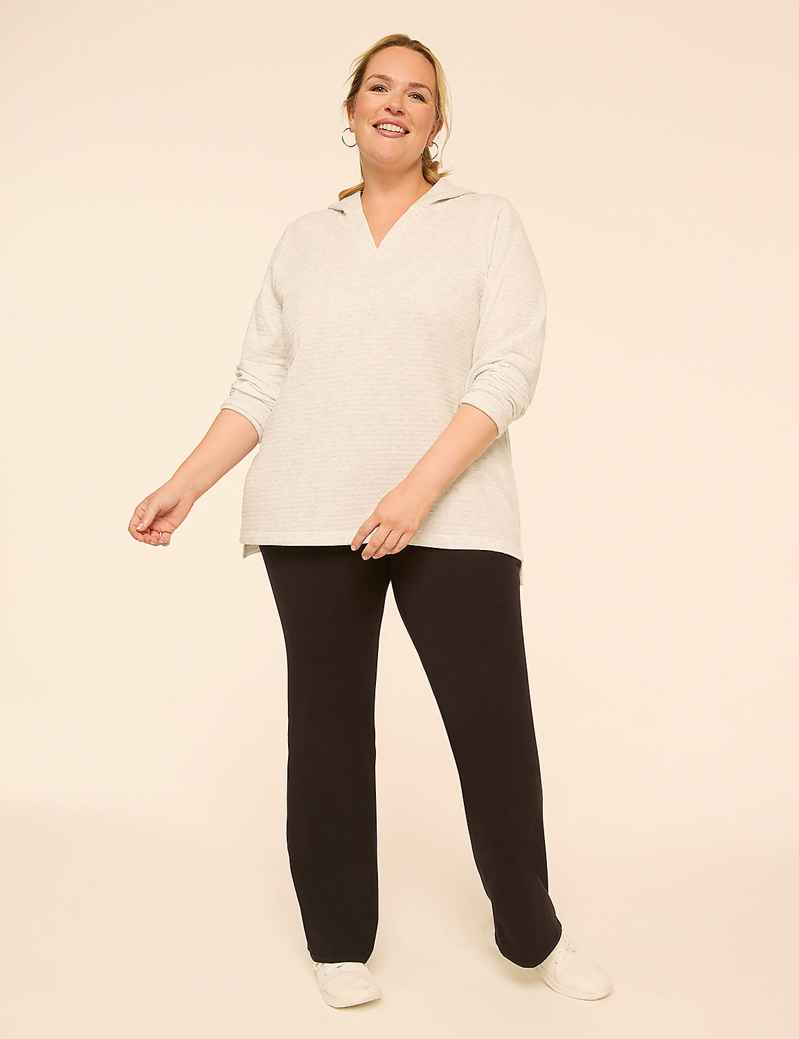 A smiling woman in a light grey hoodie and black pants stands against a plain, light-colored background. Product Image 3