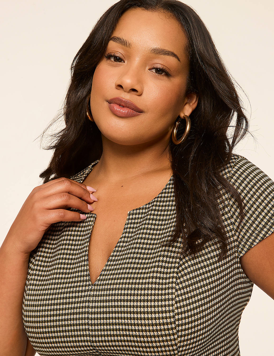 A woman with dark hair and hoop earrings in a checkered dress poses against a plain, light-colored background. Product Image 3