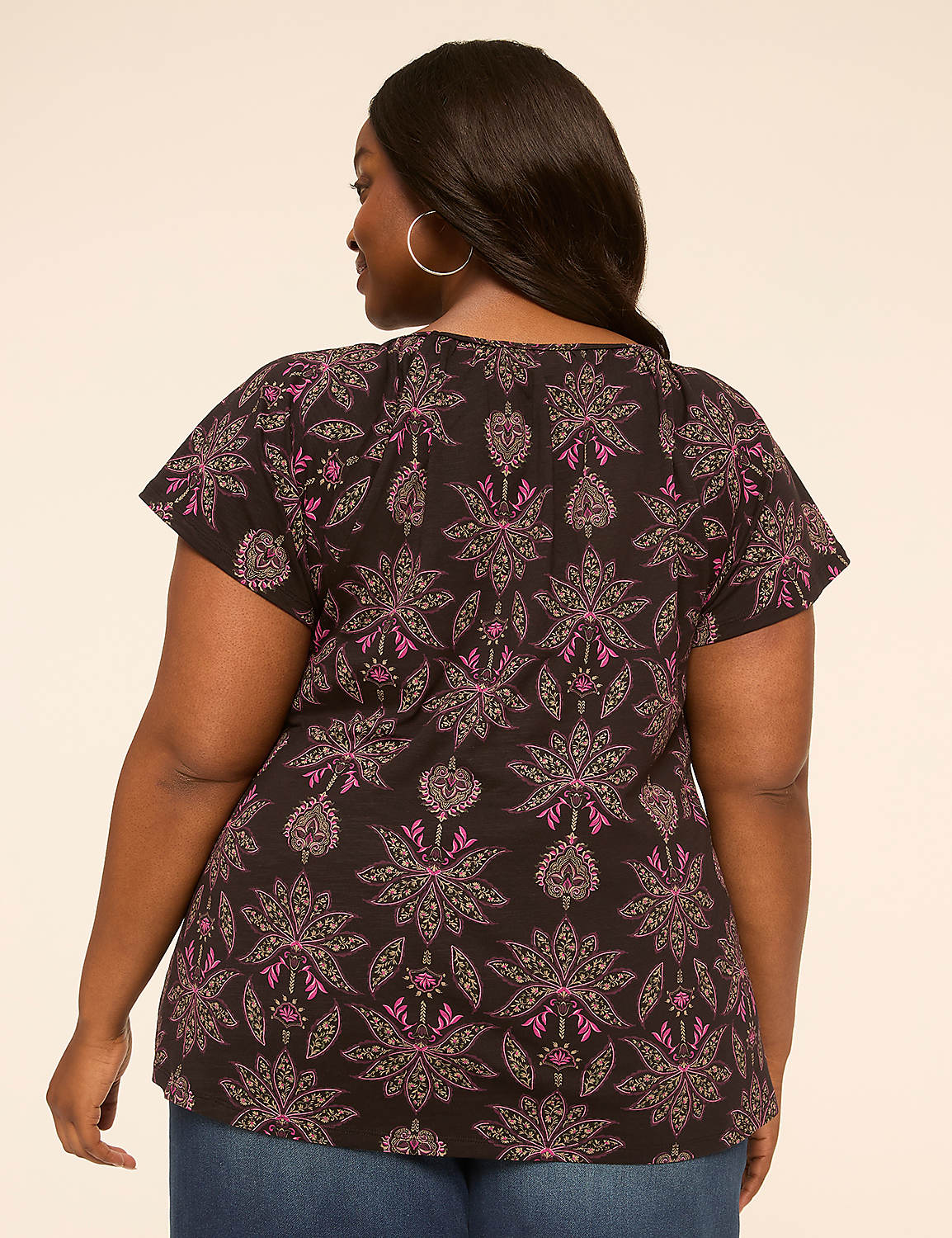 A woman in a patterned top and jeans stands against a plain, light-colored background. Product Image 2