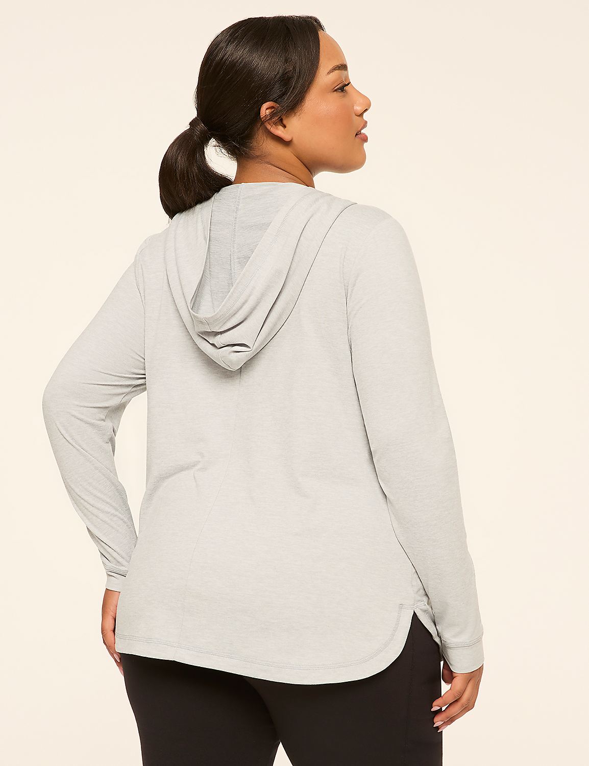 A woman in a light gray hooded shirt and black leggings stands against a plain, light-colored background. Product Image 2