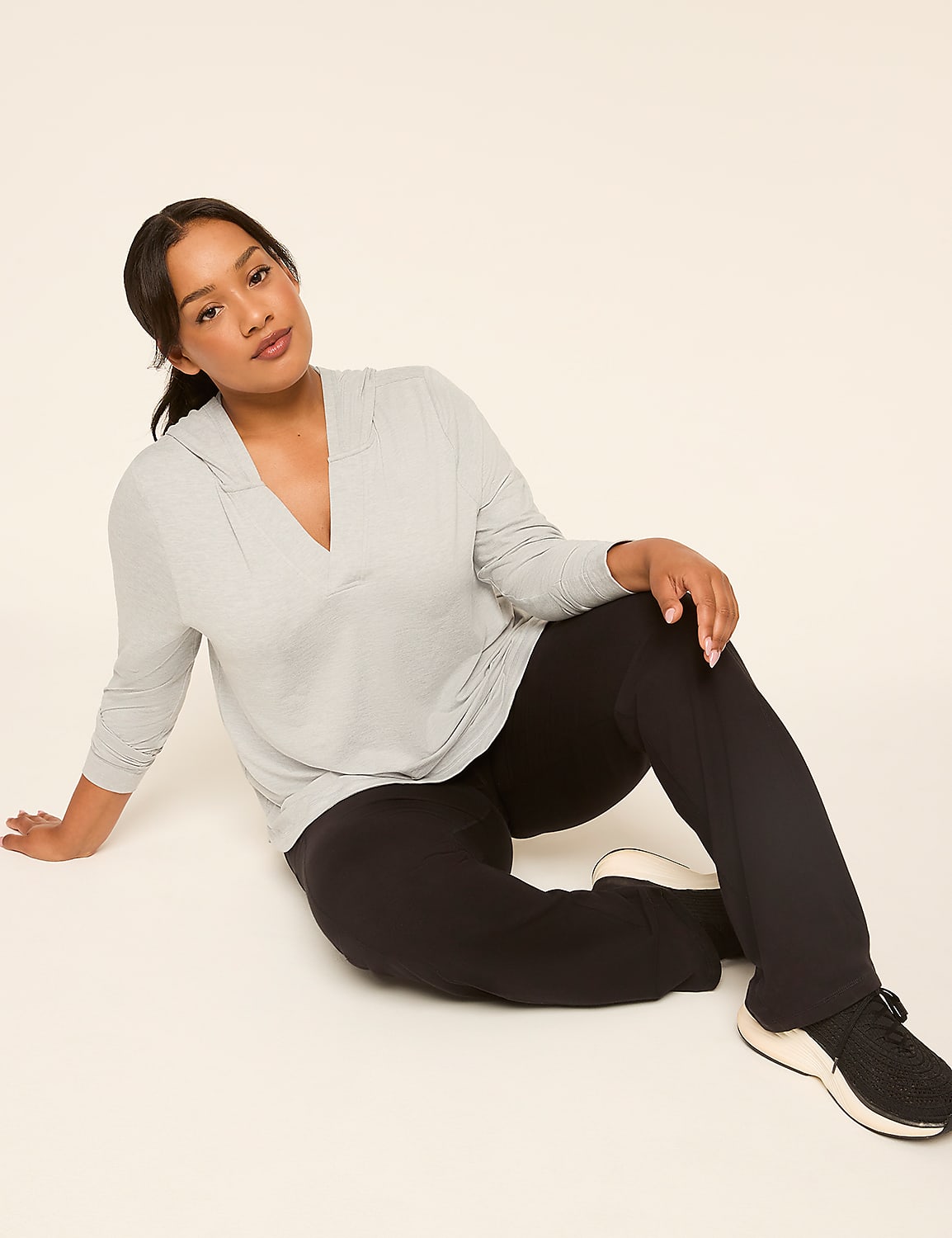 A woman in a grey hoodie and black pants sits on a light-colored floor against a plain background. Product Image 3