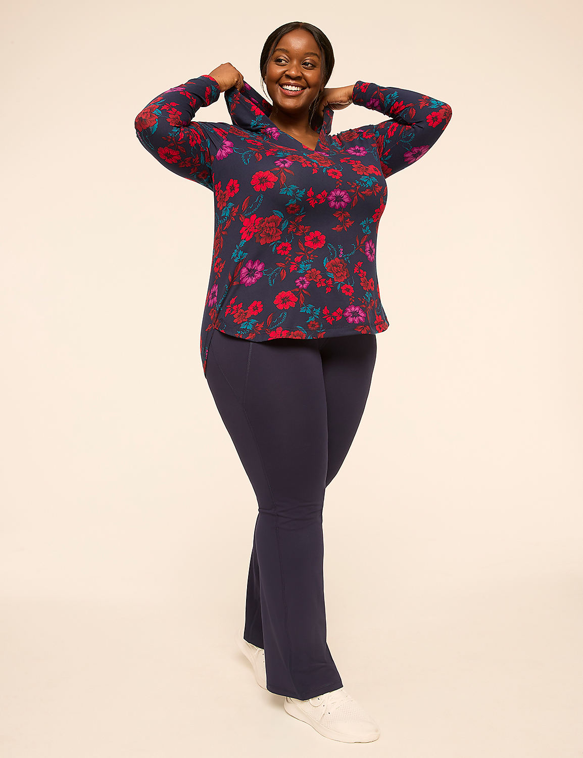 A smiling woman in a floral hoodie and navy pants stands against a plain, light-colored background. Product Image 3